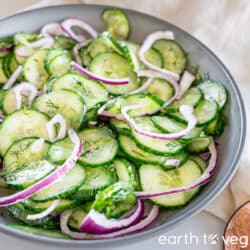 Gurkensalat piled in a dark grey bowl.
