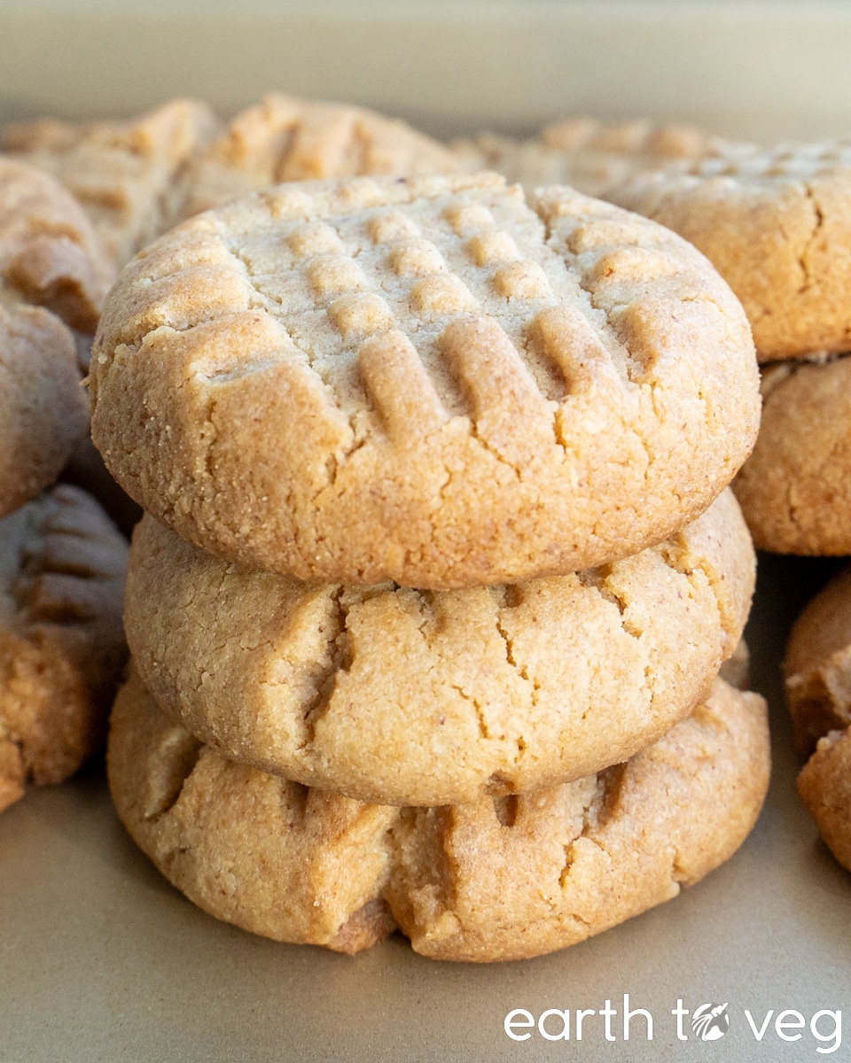 A stack of peanut butter cookies on a golden baking tray.