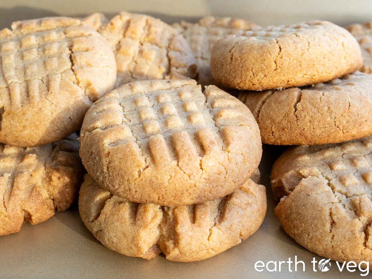 Pile of classic vegan peanut butter cookies on a metallic gold baking sheet.