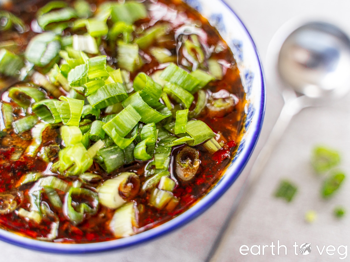 A blue china bowl full of spicy hot pot dipping sauce.