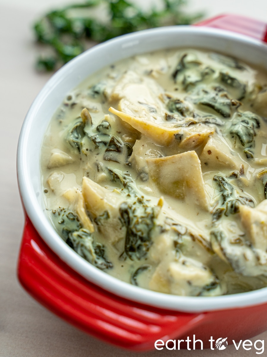 A ceramic cocotte full of melty vegan artichoke dip.