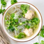 A bowl of vegan fish ball soup on a white marble countertop.