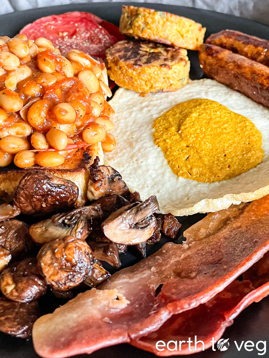 Full British vegan fry up served on a black plate.