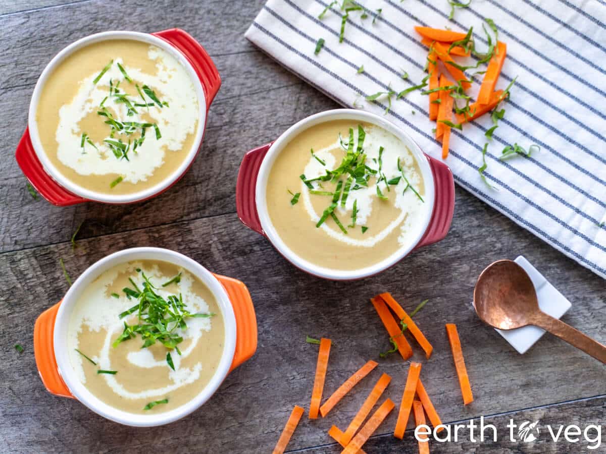 Three small bowls of vegetable marrow soup on a wooden table.