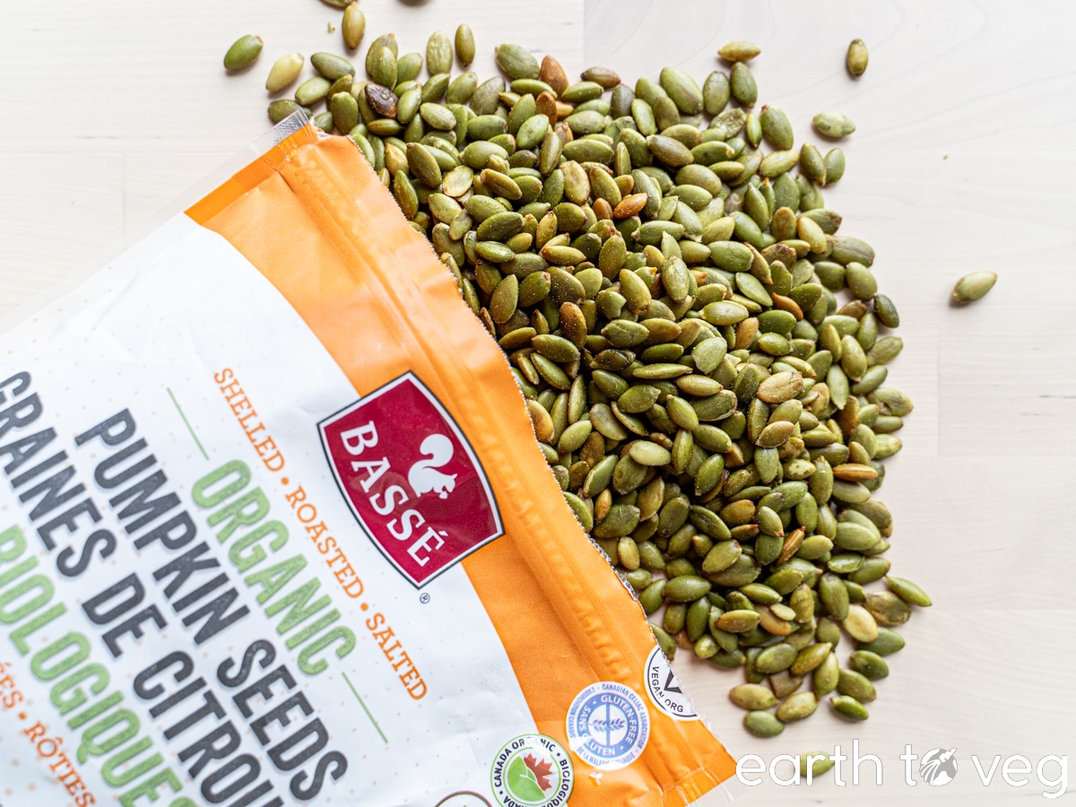 Organic roasted pumpkin seeds scattered out of a bag.