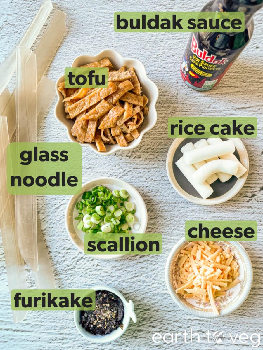 Ingredients for spicy buldak glass noodles laid out on a grey table.