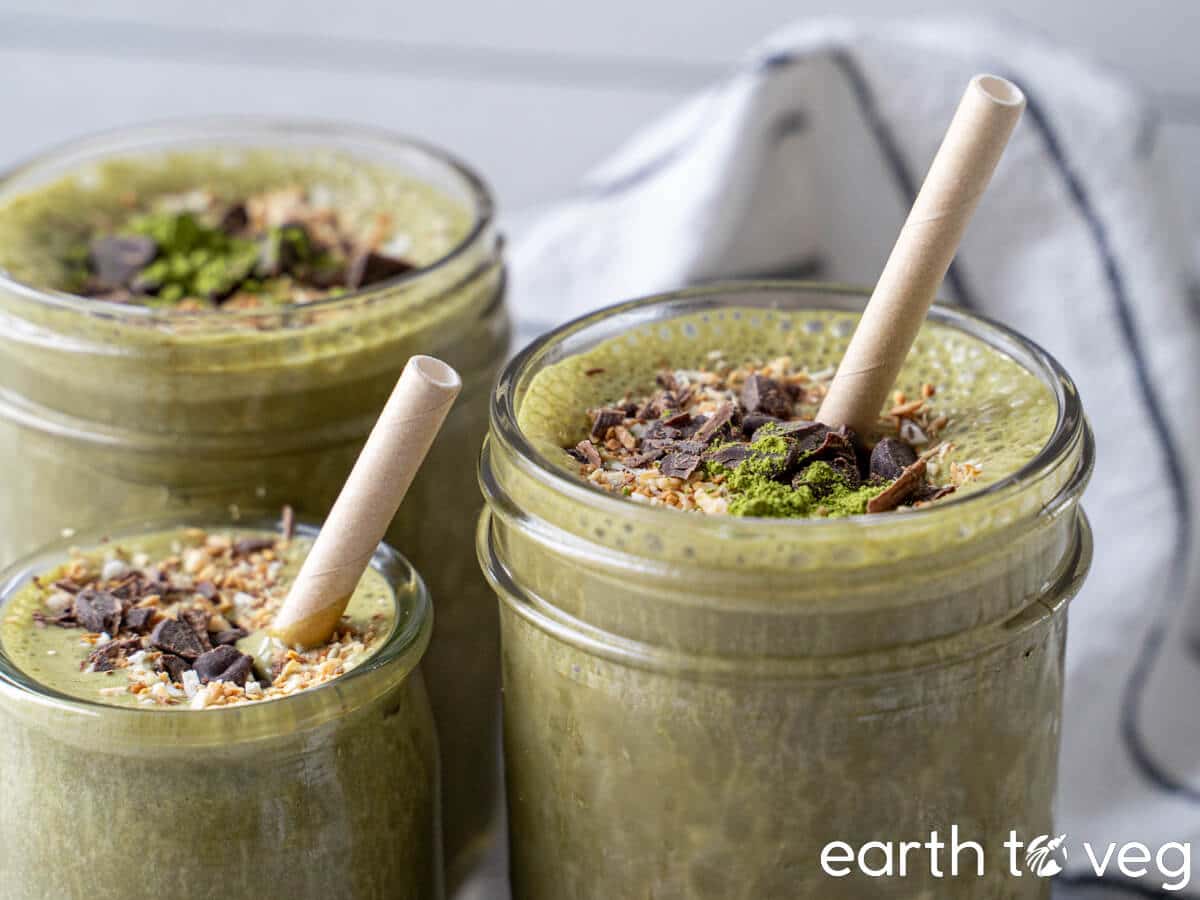 Three glasses of chocolate protein matcha smoothie topped with chocolate shavings and coconut flakes.