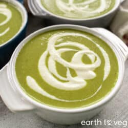 Small bowls of vegan cream of asparagus soup drizzled with vegan yogurt.