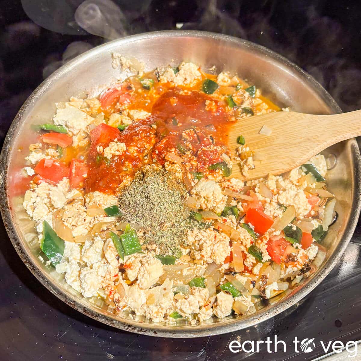 Water, tomato paste, spices, and chipotle peppers are stirred into the pan.