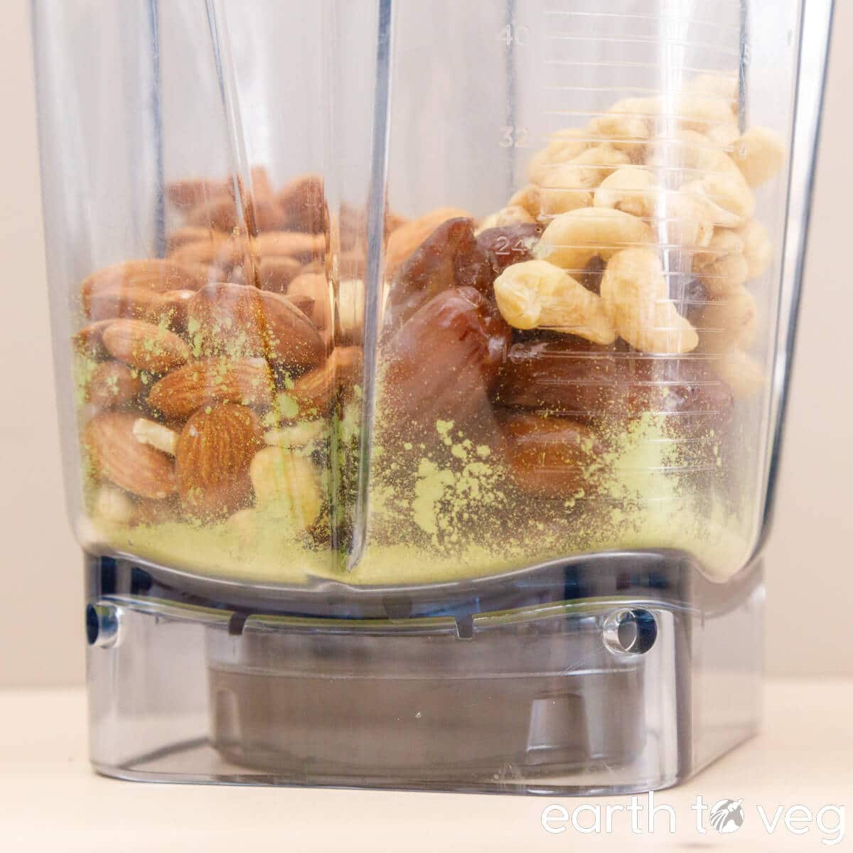 Almonds, cashews, matcha, and dates added to a blender.