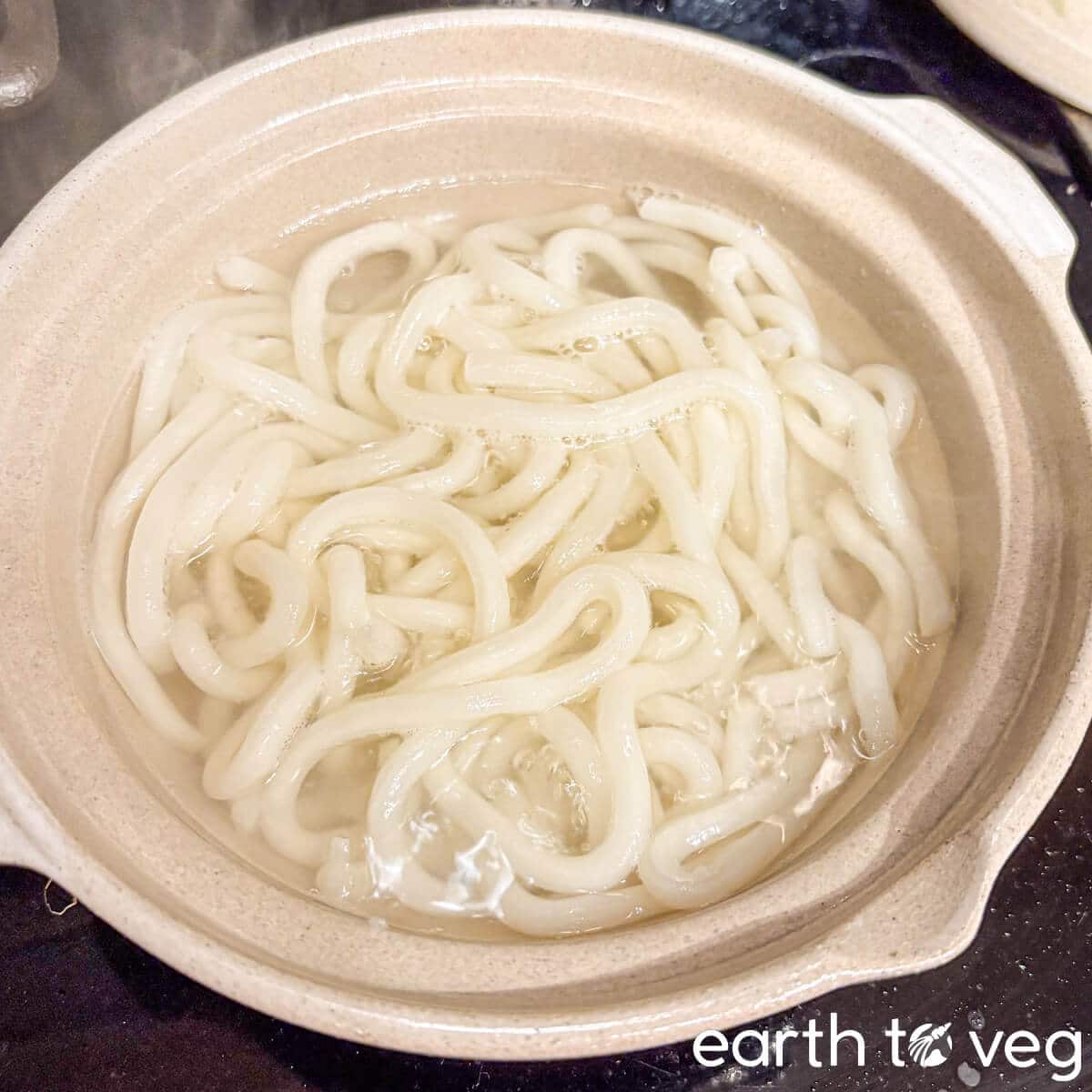 Udon noodles boiling in the pot.
