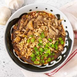 A bowl of maitake mushroom ramen topped with diced scallions.