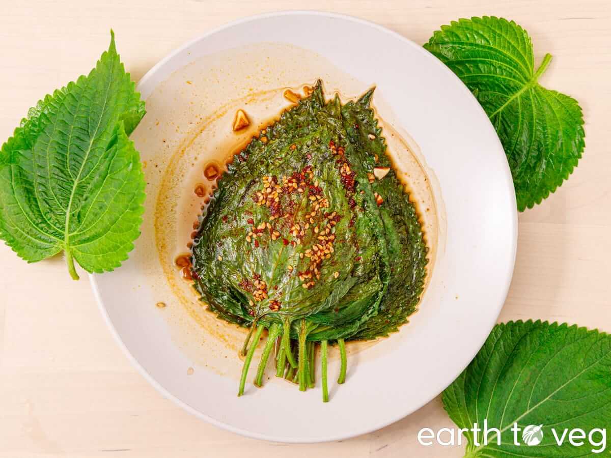 A plate of marinated Korean perilla leaves on a wooden table.