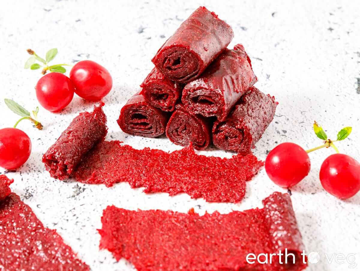 Sour cherry fruit leather roll ups next to fresh cherries.