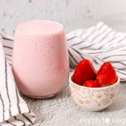 Strawberry coconut smoothie in a glass with fresh strawberries on the side.